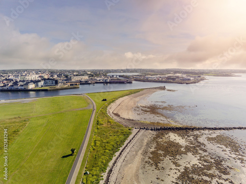Walking path in South park, Galway city, aerial drone view. Sunny day, Cloudy sky, low tide.