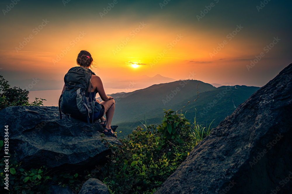 Young woman admire beautiful sunset over The Da Nang Bay and Ba Na mountains from the viewpoint, Vietnam