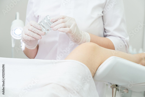 Gynecologist holding vaginal suppositories consulting patient in medical chair photo