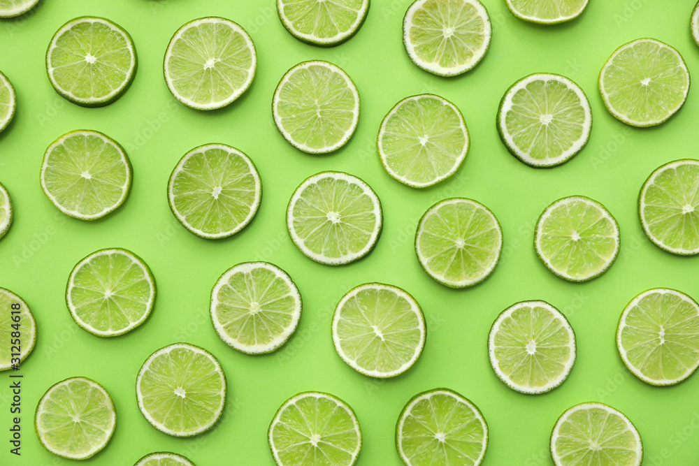 Slices of fresh juicy limes on green background, flat lay