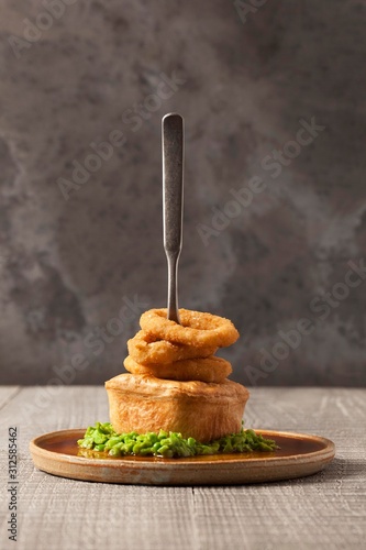 Tableau sur toile A meat pie with crushed peas, onion rings and a fork stuck in the top