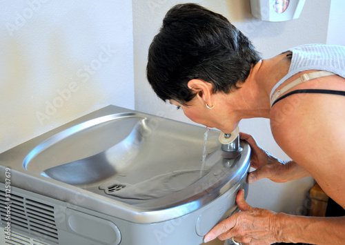 Obraz na plátně Female drinking from a water fountain indoors.
