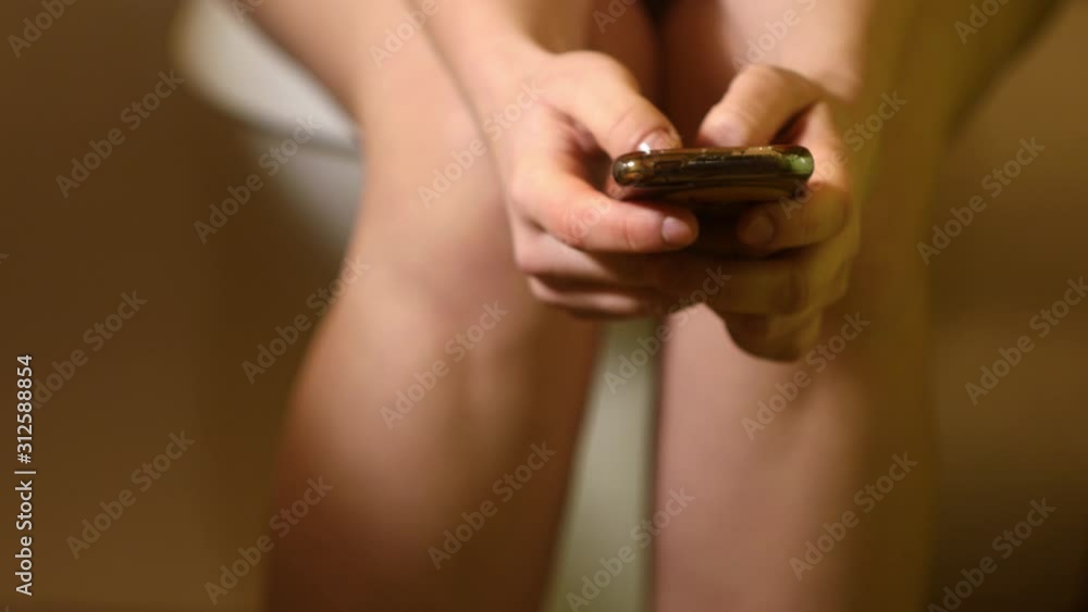 Close up woman sitting on toilet with smart phone. Chatting on phone. Playing games on phone. 4k video Close up woman sitting on toilet with smart phone. Chatting on phone. Playing games on phone. 4k video
