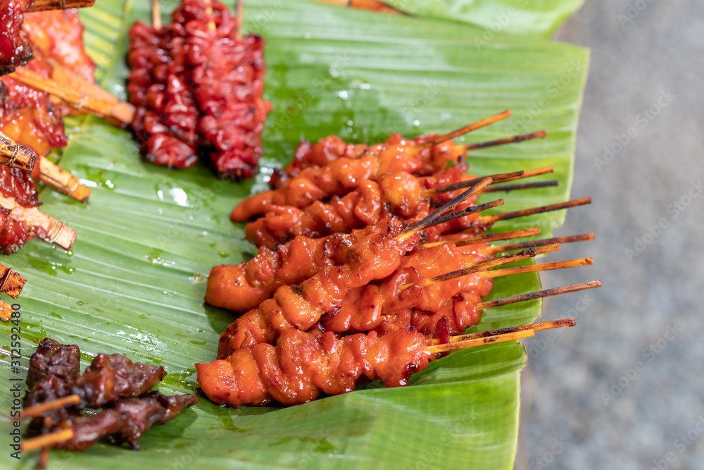 Grilled chicken on skewers placed on a banana leaf. Grilled chicken on skewers placed on a banana leaf.