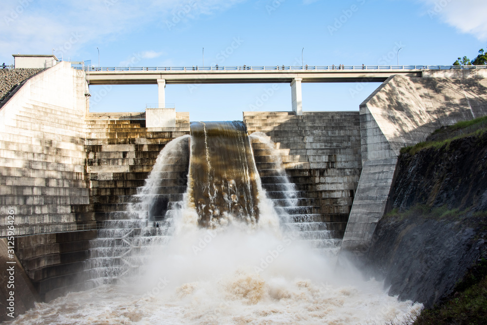 Water flowing from dam as people watch overhead Water flowing from dam as people watch overhead