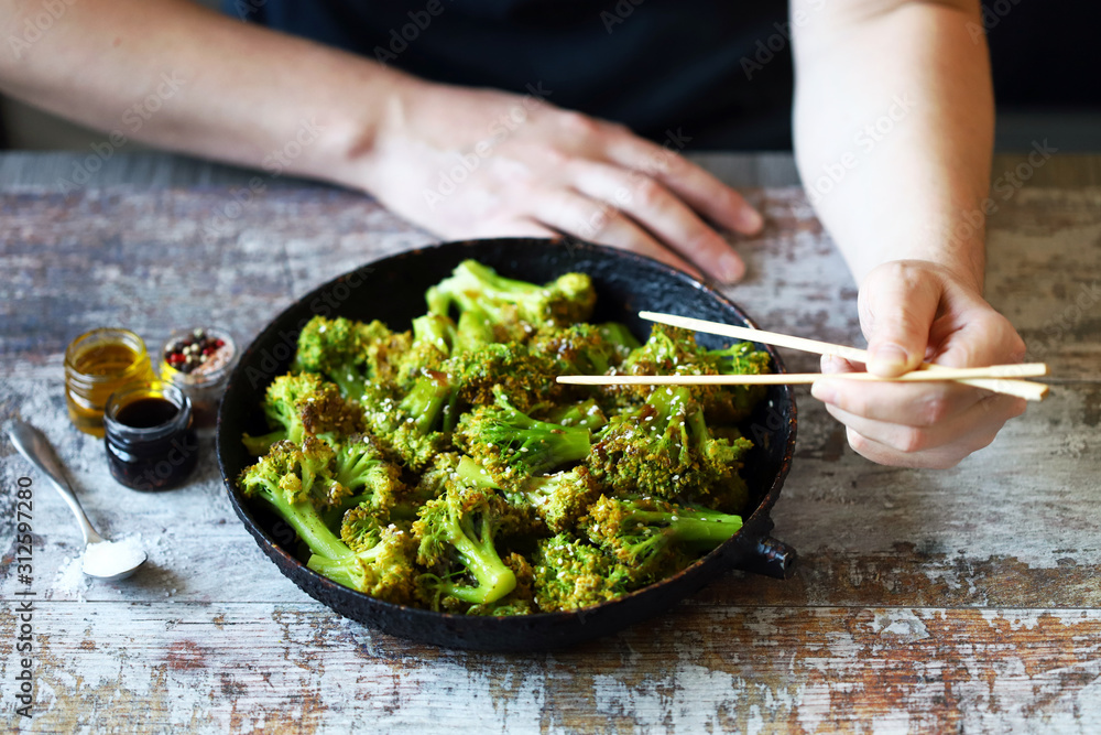 Broccoli cooked in a pan. Healthly food. A man with chopsticks eats broccoli. Broccoli cooked in a pan. Healthly food. A man with chopsticks eats broccoli.