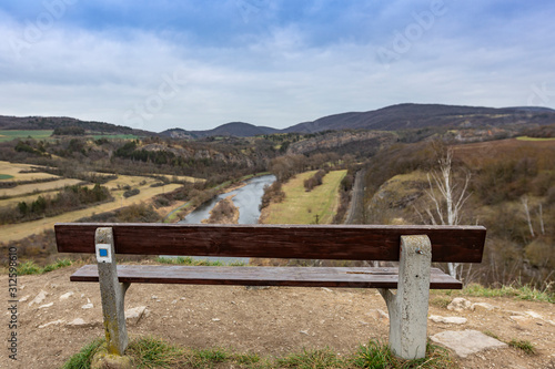 Bench on Tetín hillfort above the Berounka river near the town of Beroun in the Central Bohemian region. The bench has a blurred winter landscape without snow as a background.
