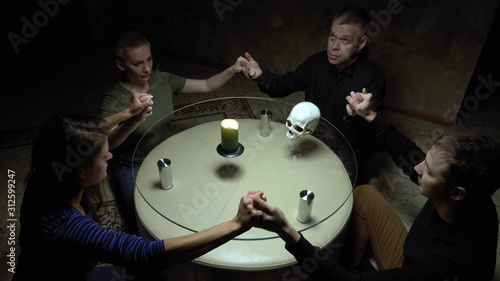 A session of spiritualism group of people sitting at a round table holding hands