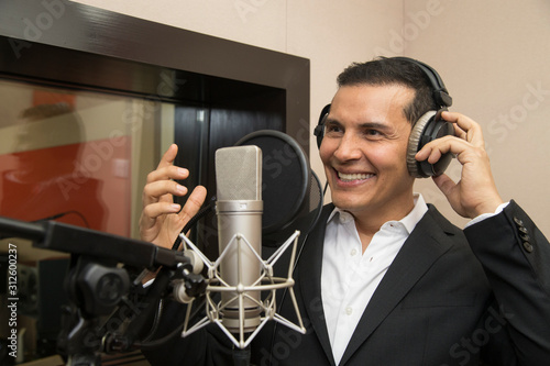 actor and radio announcer with headphones and microphone working film dubbing, performing radio spot and singing photo