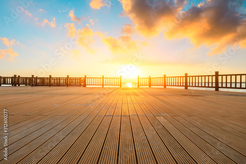 Fototapeta Naklejka Na Ścianę i Meble -  Lakeside wood floor platform and sky clouds at sunset.