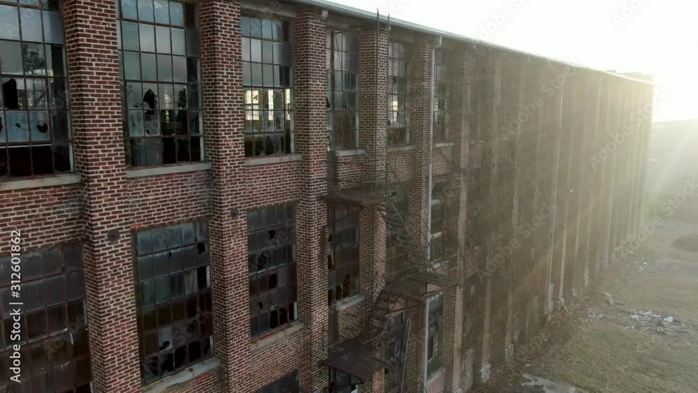 Mysterious rundown brick building with broken windows, intense morning sunlight, fire escape, aerial dolly shot Mysterious rundown brick building with broken windows, intense morning sunlight, fire escape, aerial dolly shot