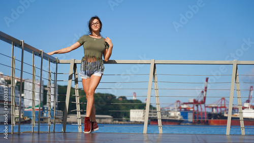 young beautiful girl on the observation deck in the port. Model in life style walks on the promenade on a sunny day. fun, smile.