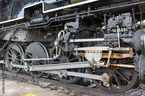 A close up of the working gears and wheels of a steam locomotive