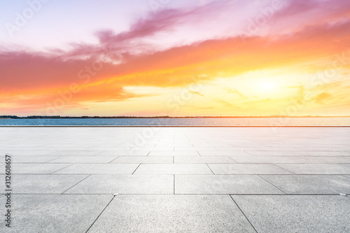 Empty square floor and lake with dreamy clouds at sunset.