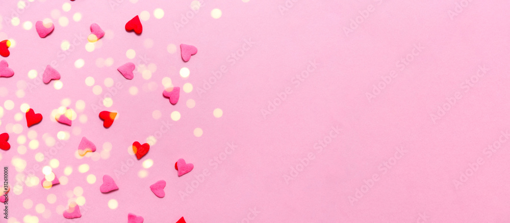 Two tone heart sprinkles on the solid pink background with light festive bokeh. Romance, love, Valentines and mother's day concept. Flat lay, horizontal wide screen banner format with place for text