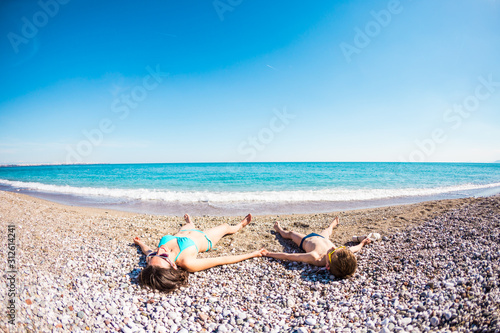 Fototapeta Naklejka Na Ścianę i Meble -  The boy with his mother sunbathe on the beach.