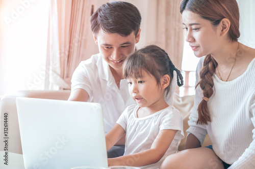 Happy Asian family using laptop in living room