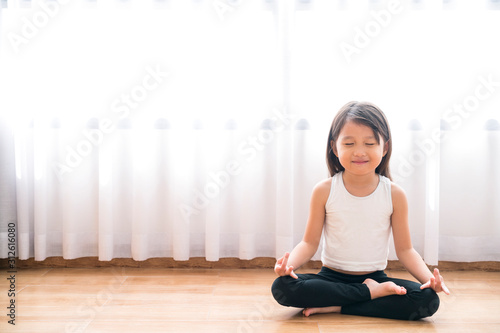 Fototapeta Naklejka Na Ścianę i Meble -  asian little cute girl do a yoga at home with space for add text