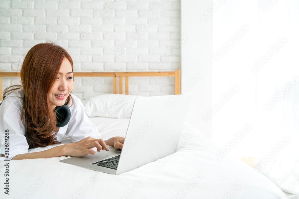 Beautiful Asian woman using laptop n bed after wake up for checking email and social media, Asian family and technology concept Beautiful Asian woman using laptop n bed after wake up for checking email and social media, Asian family and technology concept
