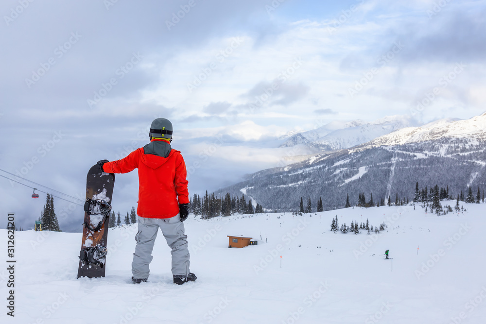 Male Snowboarder is riding down a ski run in wintertime. Taken on Whistler Mountain, British Columbia, Canada.