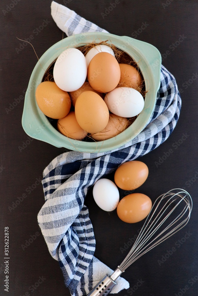 Poultry farm concept. Fresh brown and white eggs with hay on rustic wood background with cloth and whisk. Top view. Rural still life, natural organic healthy food Poultry farm concept. Fresh brown and white eggs with hay on rustic wood background with cloth and whisk. Top view. Rural still life, natural organic healthy food