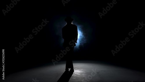 Silhouette of a young man dancer dancing in style Michael Jackson on a blue background of smoke. Close up, slow motion. photo