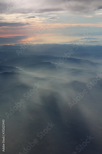 spectacular sunset seen from an airplane with the sun reflecting off a river and the  mountains in the background