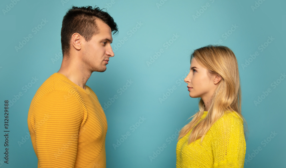 They look is serious. Alluring a couple in yellow sweaters is posing in profile and looking into each other’s eyes. They look is serious. Alluring a couple in yellow sweaters is posing in profile and looking into each other’s eyes.