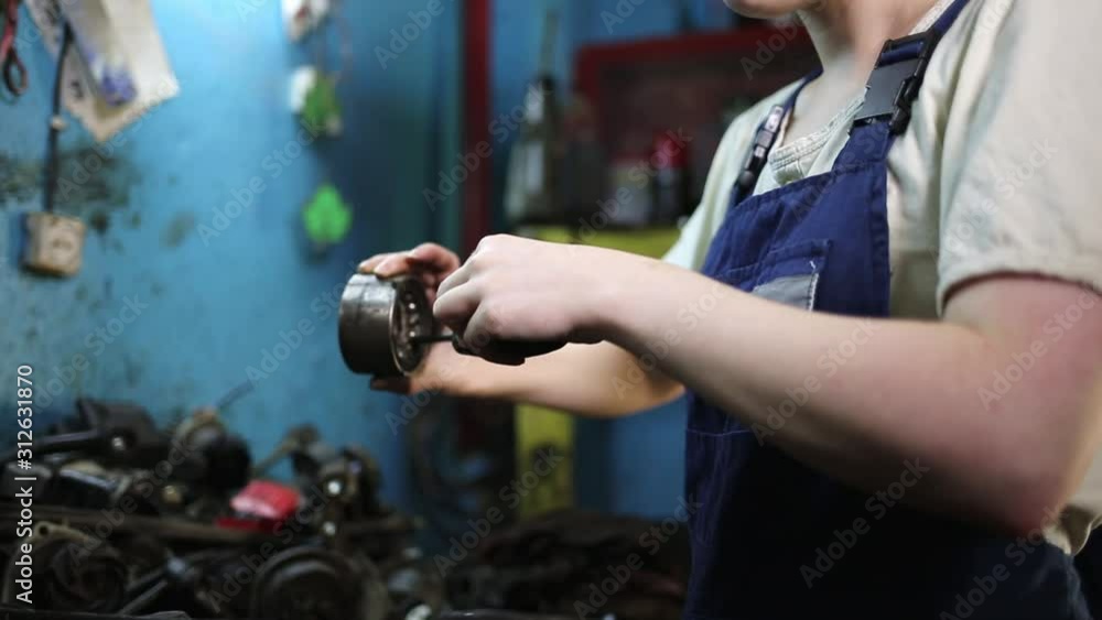 The concept of gender equality. Young pretty woman in work uniform, checking the bearing. Work in an auto repair shop. Hands close up The concept of gender equality. Young pretty woman in work uniform, checking the bearing. Work in an auto repair shop. Hands close up