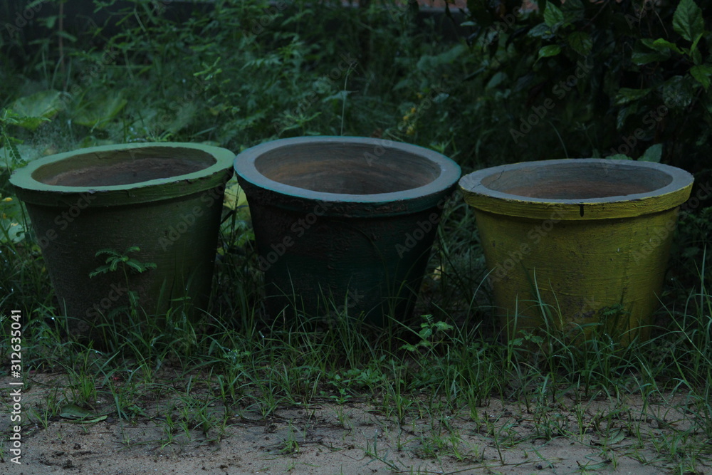 Three old rusted abandoned colored flower pots or plant pots on the garden