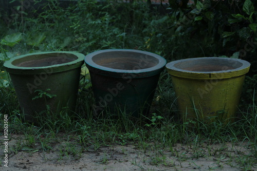 Three old rusted abandoned colored flower pots or plant pots on the garden