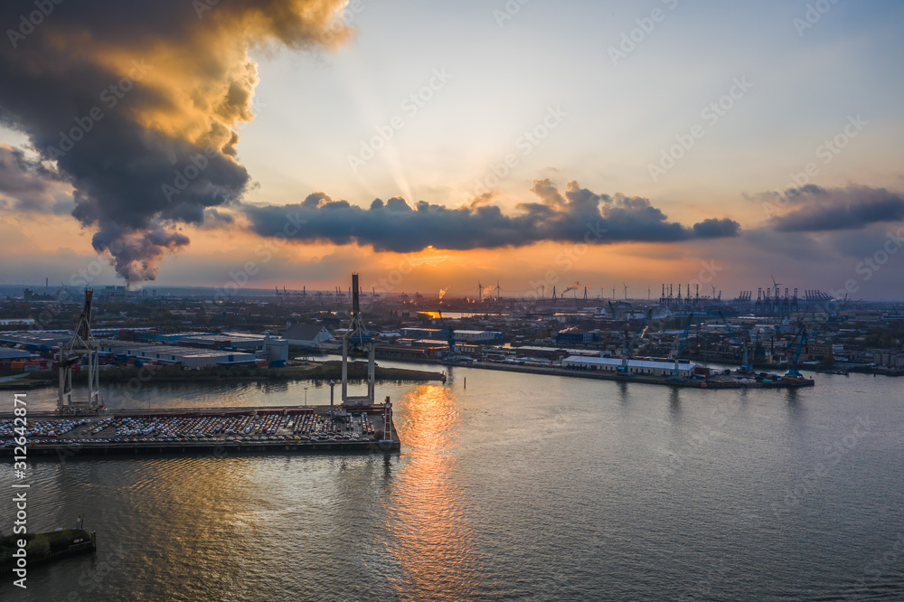 Sunset with dramatic clouds at port of Hamburg with heavy-lifting crane Sunset with dramatic clouds at port of Hamburg with heavy-lifting crane