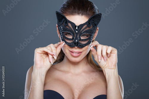 Sexy brunette woman holding mustache in catwoman mask