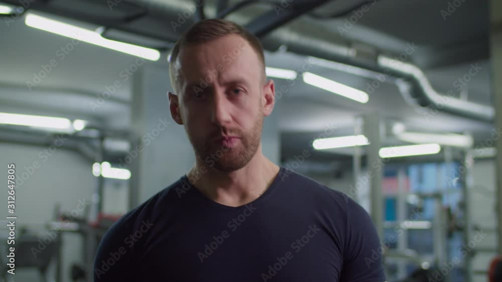 Muscular build handsome man eating protein bar containing high proportion of protein to carbohydrates and fats to build muscles after intense sport training in fitness club. Sport nutrition. Muscular build handsome man eating protein bar containing high proportion of protein to carbohydrates and fats to build muscles after intense sport training in fitness club. Sport nutrition.