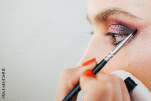 Luxurious makeup by professional makeup artist in studio. Vogue, cosmetics and glamour concept. Close up womans eyes with shimmery purple smokey eyes makeup.
