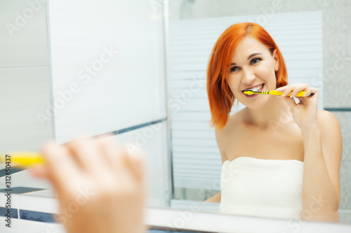 Woman with red hair in bathroom use care products