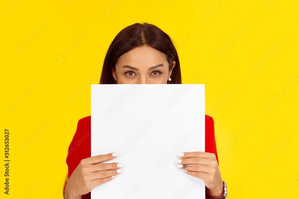 Woman holding a board paper hiding her smile behind it Woman holding a board paper hiding her smile behind it