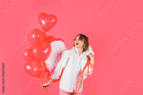 Happy Valentines Day. Love concept. Sexy woman with cupid angel wings holds red heart balloons. Valentines day angel. Saint Valentines Day celebration. Valentines cupid with wings. February 14. Cupid. © Svitlana