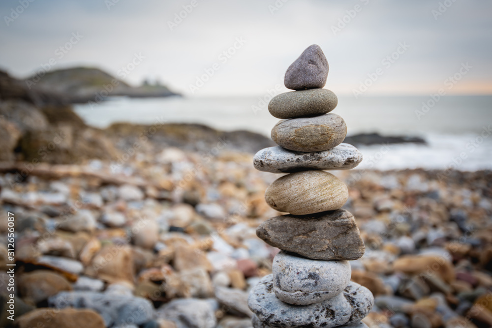 Stack of stones against blurred seascape on a beach swansea wales, space for text. Zen concept