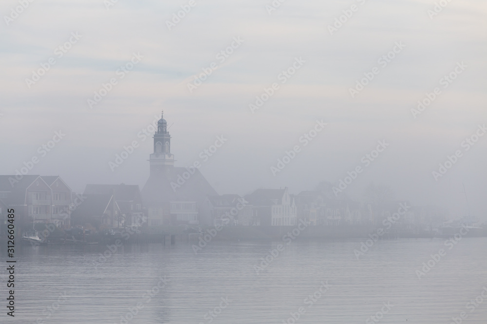 The dutch village Lekkerkerk covered in morning fog