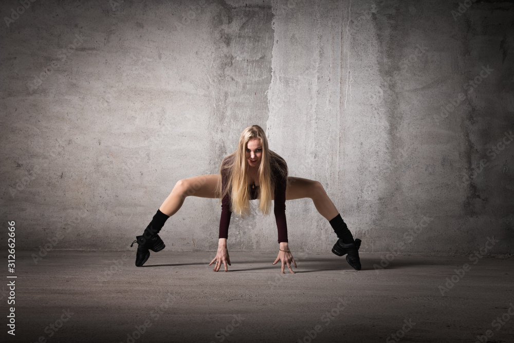 Blonde dancer stands on fingers on a gray background, dance pose, dance, body shape, fitness, training, strength