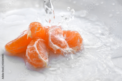 peeled mandarin in drops of water on a white plate