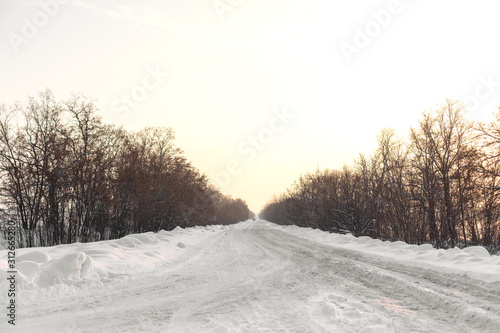 Winter poorly cleared road. Road in the countryside strewn with snow. Winter landscape with snowdrifts