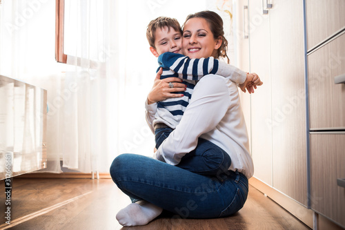 Beautiful young mom and her son hugging each other tightly.