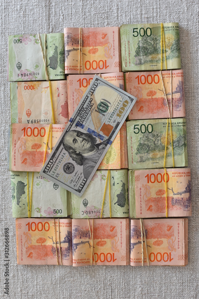 100 dollar bill with Argentine peso bills, symbolic for money exchange rate
