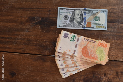 Fotografie 100 dollar bill with Argentine peso bills, symbolic for money exchange rate