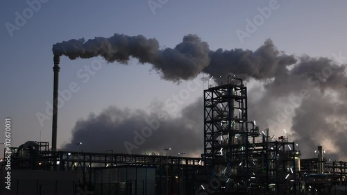 Dark hot smoke coming out of an industrial chimney of a chemical plant. Air pollution and global warming photo