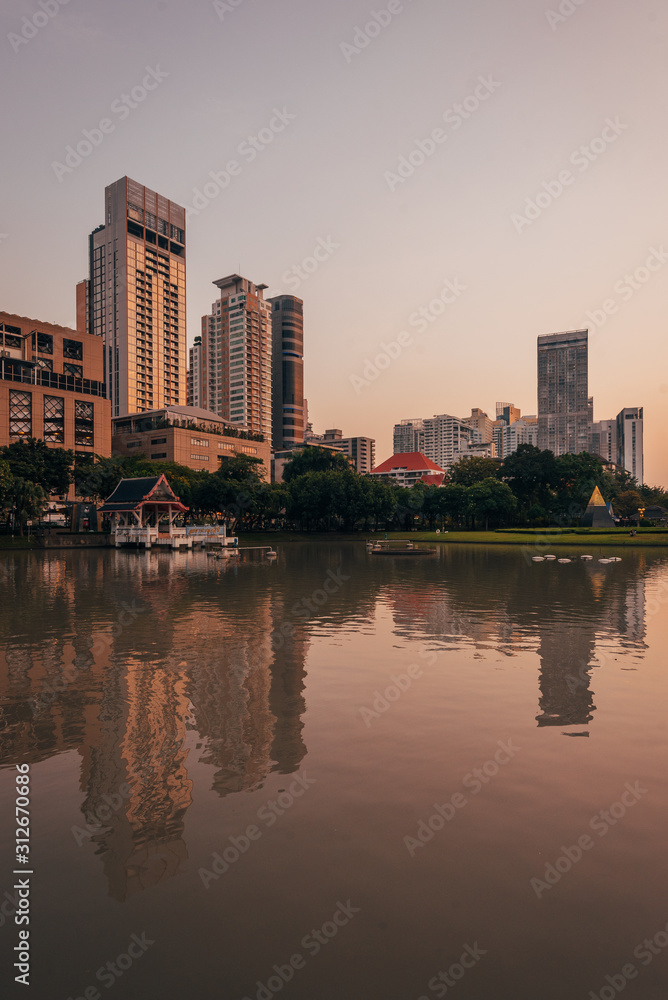 Lake and modern buildings on Sukhumvit Road at sunset, at Benchasiri Park, in Bangkok, Thailand
