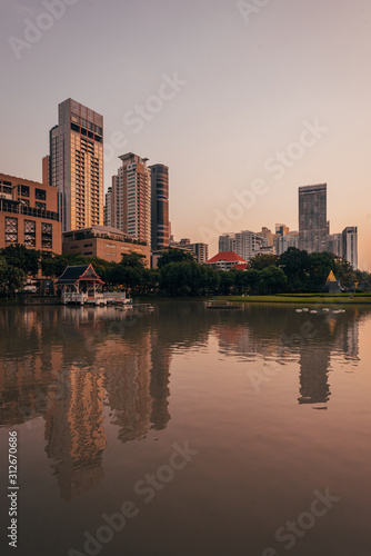 Lake and modern buildings on Sukhumvit Road at sunset  at Benchasiri Park  in Bangkok  Thailand