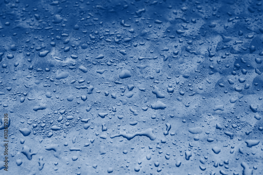 blue water drops texture on the glass background. Classic blue toning trend 2020